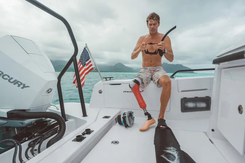 Slide: The Image of Man on 2023 Axopar 37 Sun-Top Wet Bar boat with prosthetic leg, holding snorkel gear. - 10