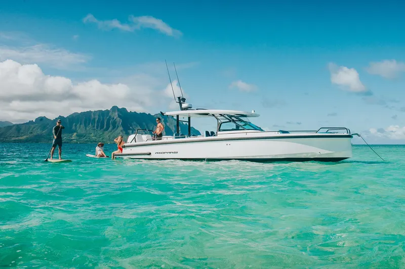 Slide: The Image of 2023 Axopar 37 Sun-Top Wet Bar in turquoise waters, with people enjoying water activities. - 11