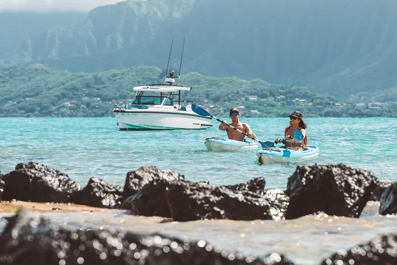 Slide: The Image of Couple kayaking near 2023 Axopar 37 Sun-Top Wet Bar boat in scenic coastal waters. - 20
