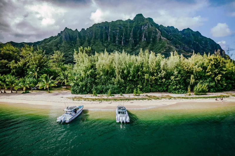 Slide: The Image of Two 2023 Axopar 37 Sun-Top Wet Bar boats on a tropical beach with lush mountains. - 22
