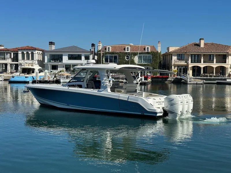 Slide: The Image of 2019 Boston Whaler 350 Realm boat cruising in a scenic waterfront neighborhood. - 2