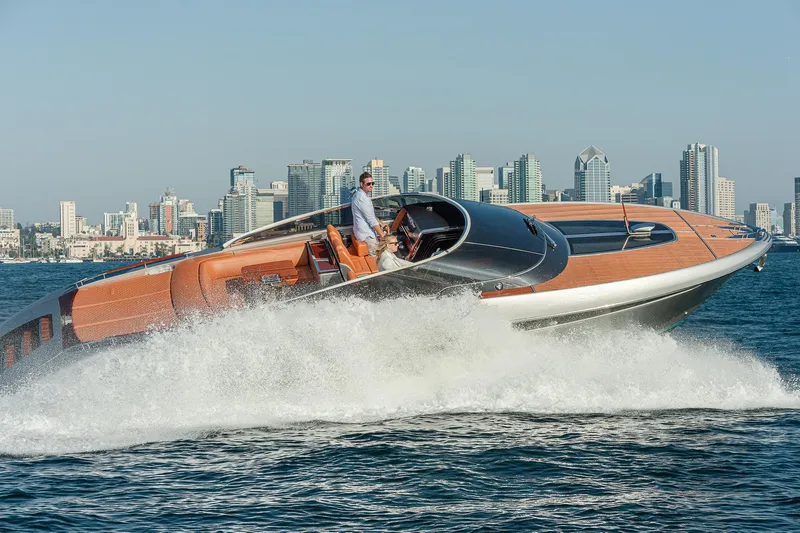 Slide: The Image of 2024 Riva 38 Rivamare yacht cruising on water with city skyline backdrop. - 2