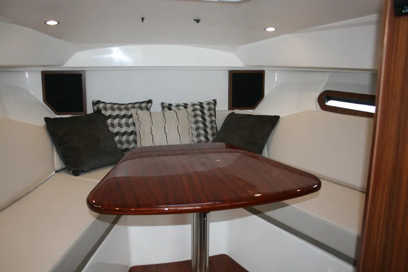 Slide: The Image of 2021 Pursuit OS 325 Offshore cabin interior with cozy seating and wooden table. - 11