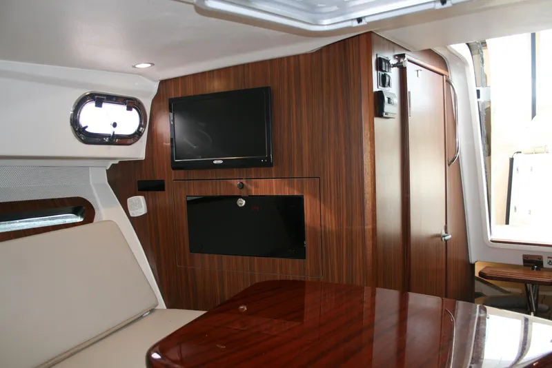 Slide: The Image of 2021 Pursuit OS 325 Offshore cabin interior with wood paneling and mounted TV. - 14