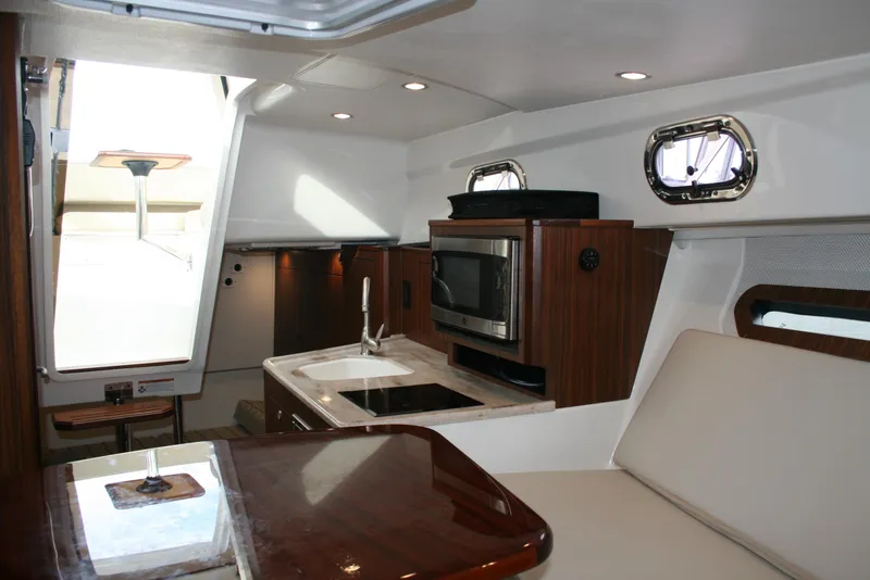 Slide: The Image of 2021 Pursuit OS 325 Offshore cabin interior with kitchenette and seating area. - 15