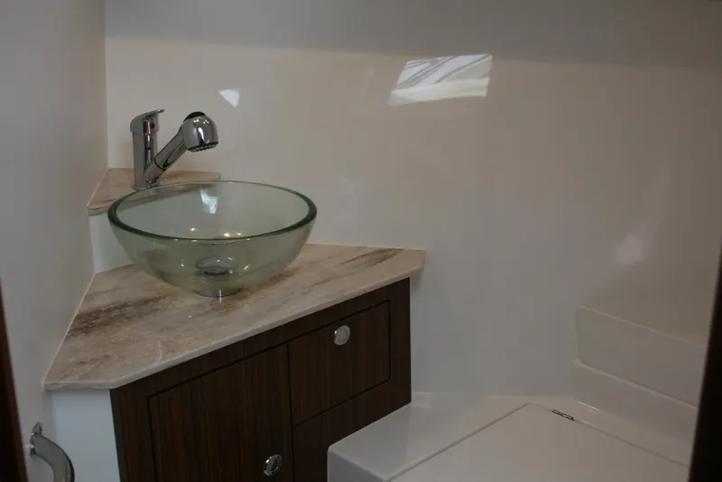 Slide: The Image of Modern bathroom in 2021 Pursuit OS 325 Offshore boat with glass sink and wooden cabinetry. - 19