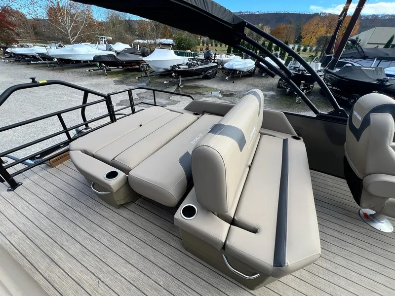 Slide: The Image of 2025 Sylvan L3 DLZ Tritoon with beige seating and cup holders, parked outdoors. - 10
