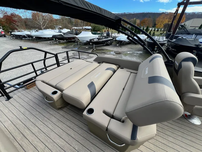 Slide: The Image of 2025 Sylvan L3 DLZ Tritoon with beige seating and cup holders, docked outdoors. - 20