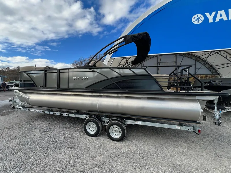Slide: The Image of 2025 Sylvan L3 DLZ Tritoon boat on trailer under blue sky. - 24