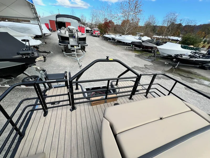 Slide: The Image of 2025 Sylvan L3 DLZ Tritoon in a boatyard, surrounded by other boats. - 27