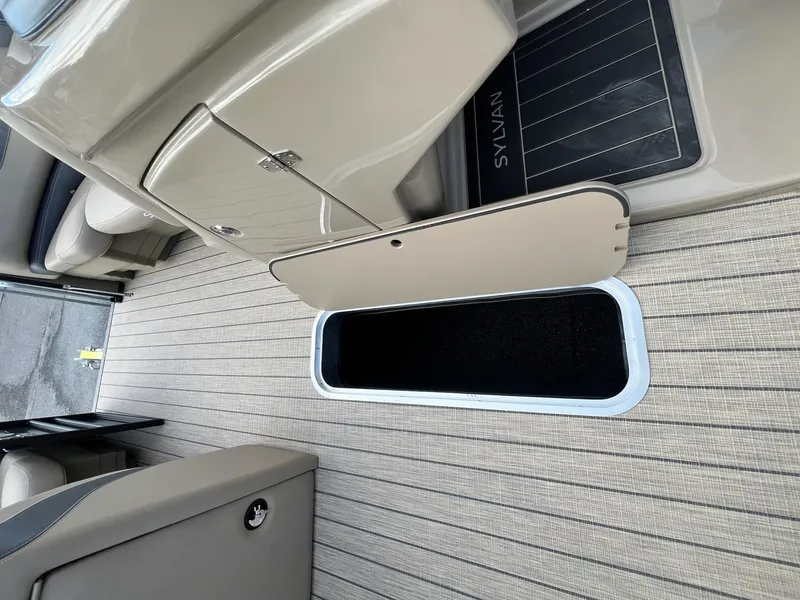Slide: The Image of 2025 Sylvan L3 DLZ Tritoon interior storage compartment with open hatch on sleek flooring. - 29