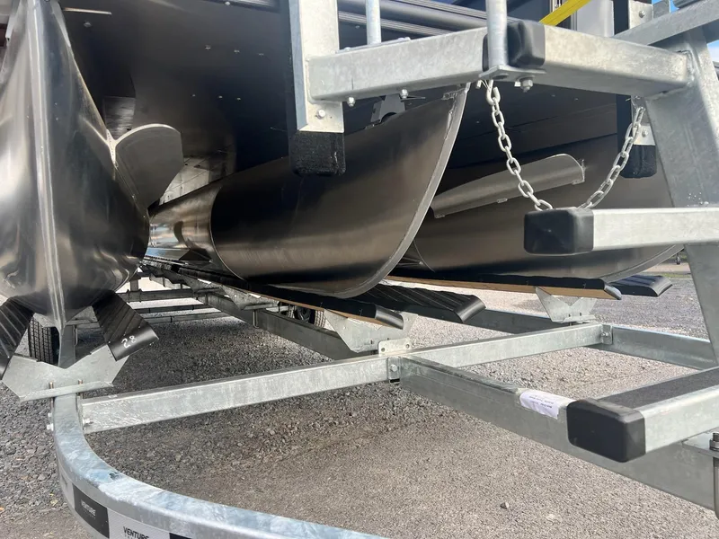 Slide: The Image of 2025 Sylvan L3 DLZ Tritoon underside on trailer, showcasing pontoons and structure. - 35