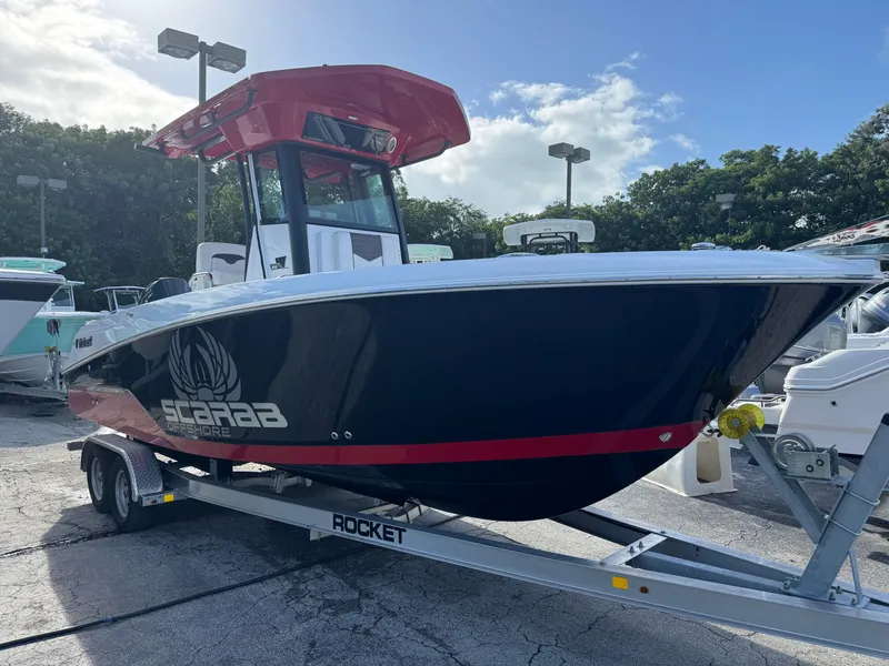 Slide: The Image of 2025 Wellcraft 243 Fisherman boat on trailer, black and red design, outdoors. - 2