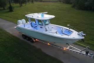 Slide: The Image of 2024 Crevalle 33 CSF boat on trailer, parked on a grassy area. - 12