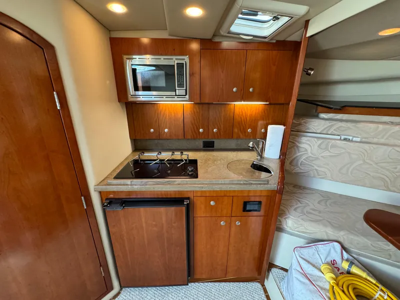 Slide: The Image of 2011 Rampage 34 IPS yacht interior with kitchenette, featuring wood cabinets, stove, and microwave. - 26