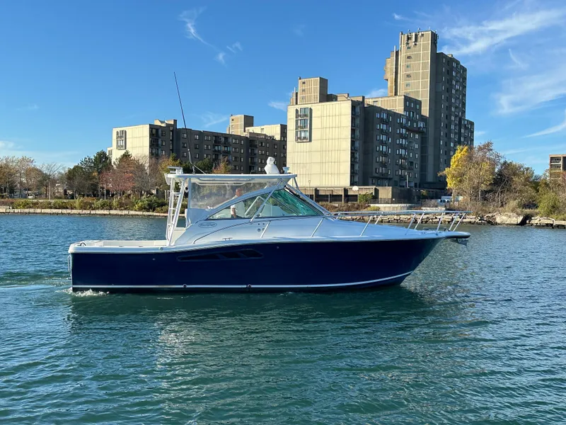 Slide: The Image of 2011 Rampage 34 IPS boat cruising on a calm urban waterway. - 5
