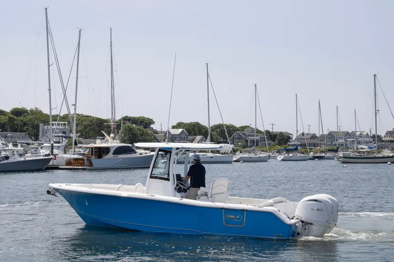 The Image of 2025 Sea Hunt Ultra 265 SE boat cruising in a marina with sailboats in the background. - 1