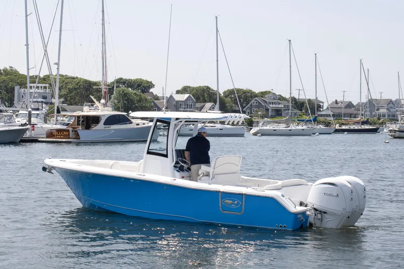 Slide: The Image of 2025 Sea Hunt Ultra 265 SE boat in marina, blue hull, outboard engines, calm water. - 6