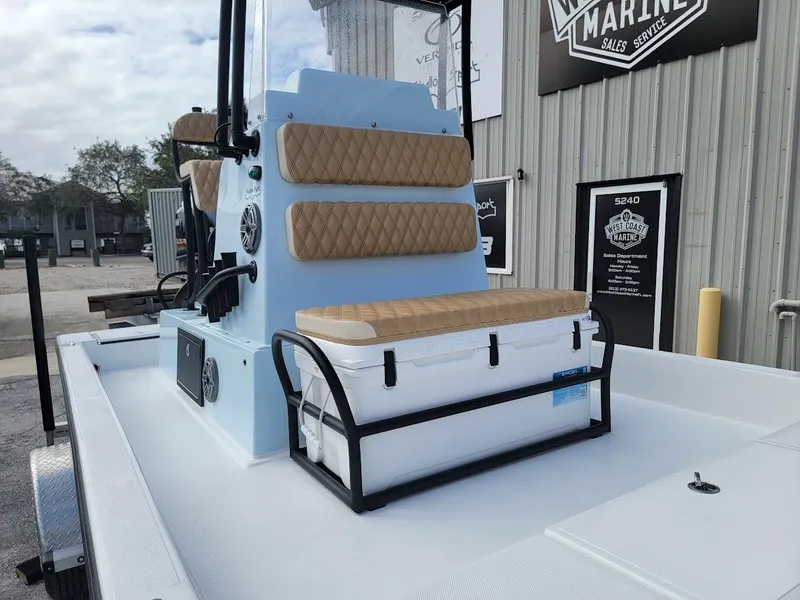 Slide: The Image of 2025 Shallow Sport 18 Sport boat with cushioned seating and storage, parked outside a marine shop. - 3