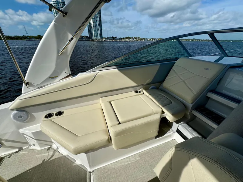 Slide: The Image of 2023 Regal 26 XO boat interior with beige seating, cup holders, and waterfront view. - 17