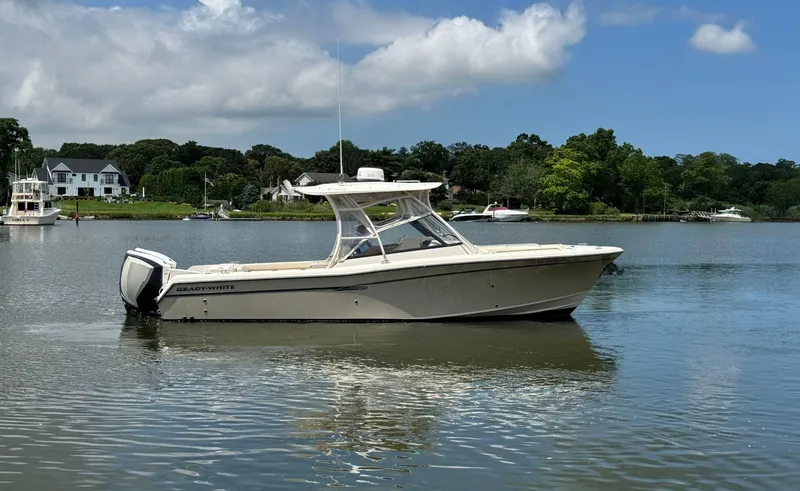 Slide: The Image of 2016 Grady-White Freedom 285 boat on calm water, surrounded by lush greenery. - 5