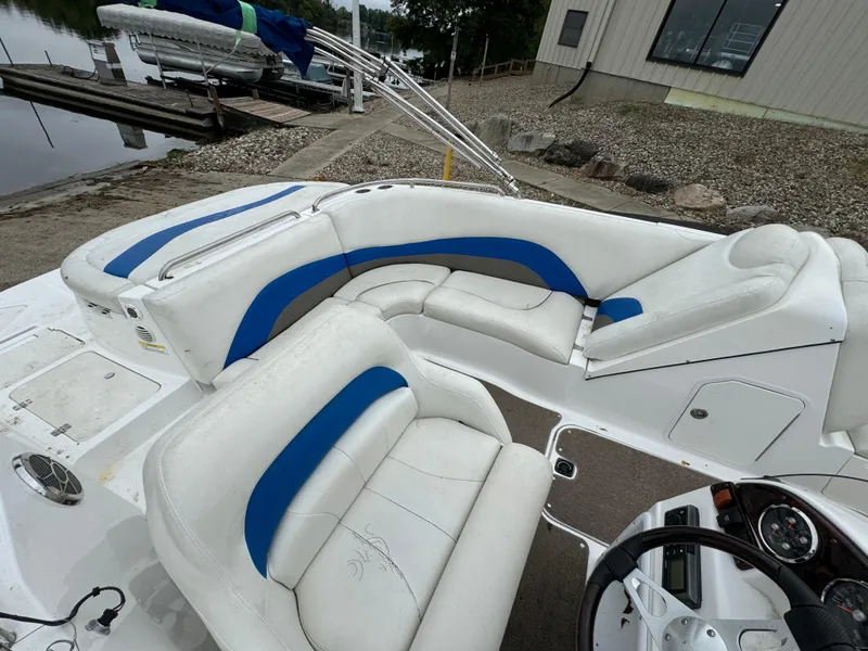 Slide: The Image of 2014 Hurricane SunDeck Sport 202 IO boat with white and blue seating, docked by a lakeside. - 3