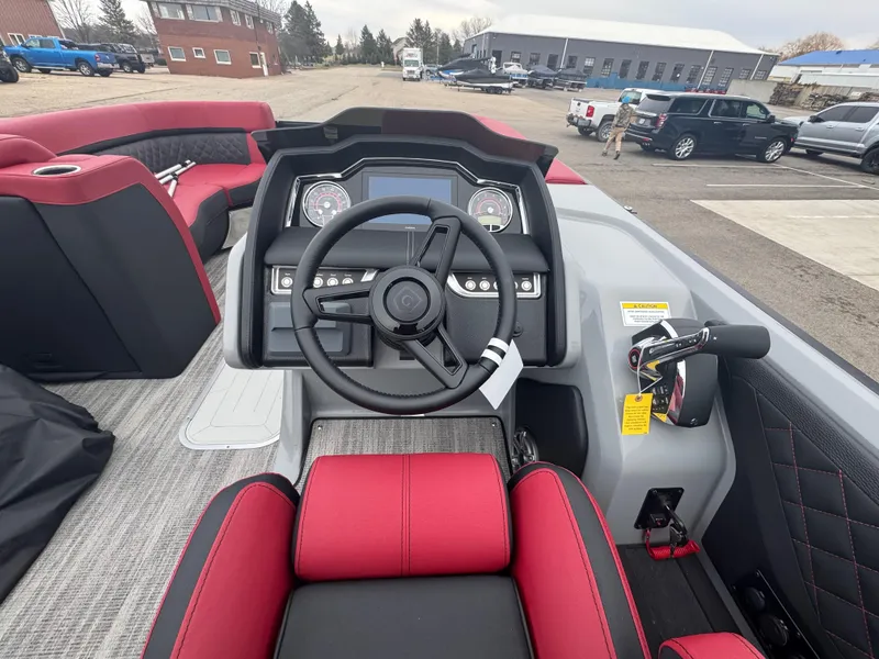 Slide: The Image of 2025 Godfrey AQUAPATIO 255SFL boat dashboard with steering wheel and red seating. - 14