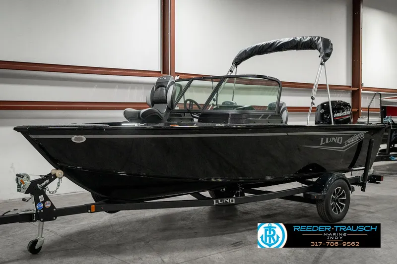 Slide: The Image of 2025 Lund 1775 Adventure Sport boat in showroom, black exterior, on trailer. - 2