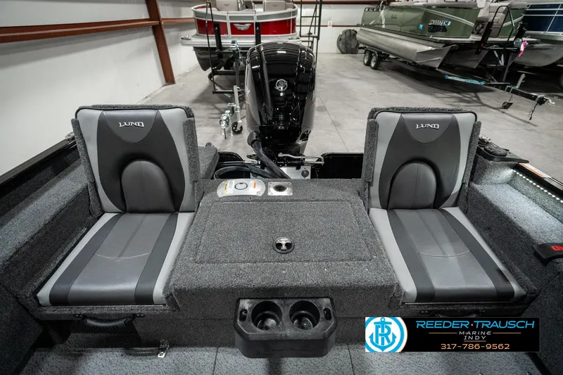Slide: The Image of 2025 Lund 1775 Adventure Sport boat interior with dual seats and motor in showroom. - 25