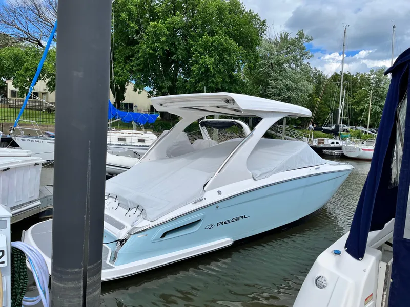 Slide: The Image of 2022 Regal 2800 Bowrider boat docked in a marina, covered and ready for use. - 1