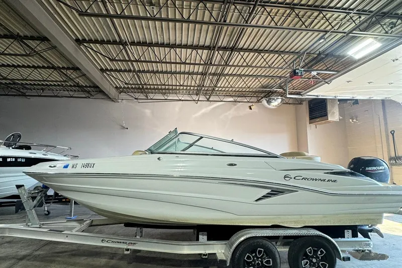 Slide: The Image of 2023 Crownline 215 XS boat on trailer in indoor storage. - 11