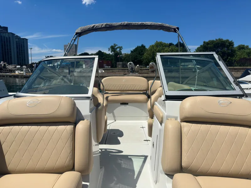 Slide: The Image of 2023 Crownline 215 XS boat with beige seating and open deck under clear blue sky. - 6