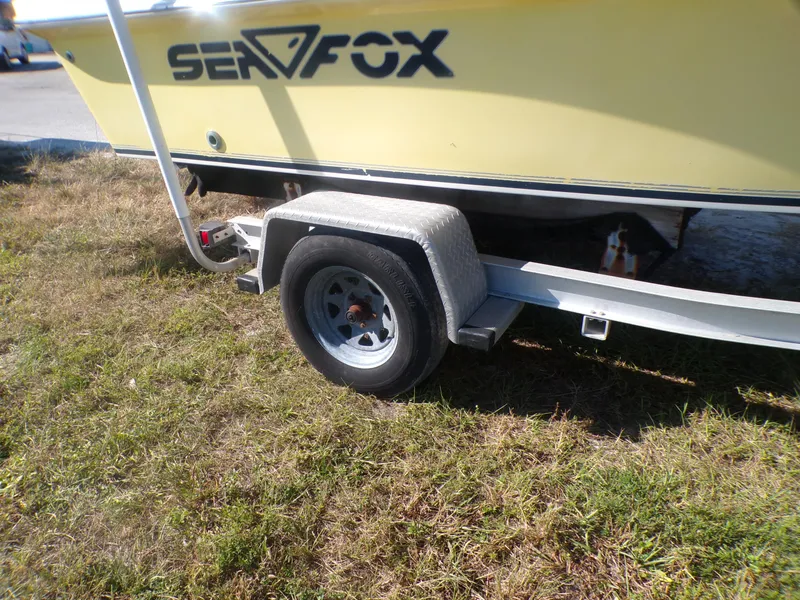 Slide: The Image of 2003 Sea Fox 197 Center Console boat on trailer, parked on grass. - 10