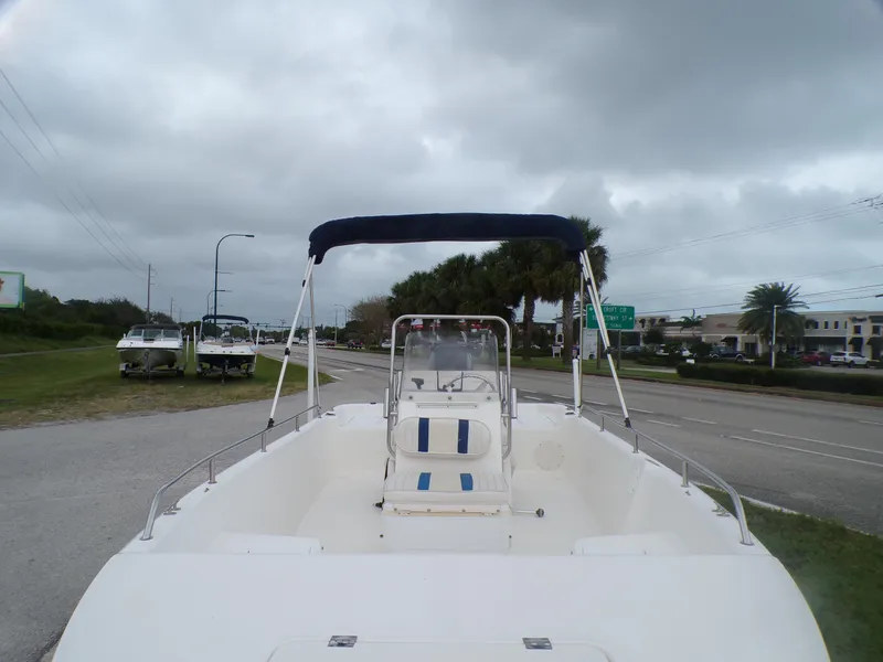 Slide: The Image of 2003 Sea Fox 197 Center Console boat with canopy on roadside, cloudy sky background. - 4