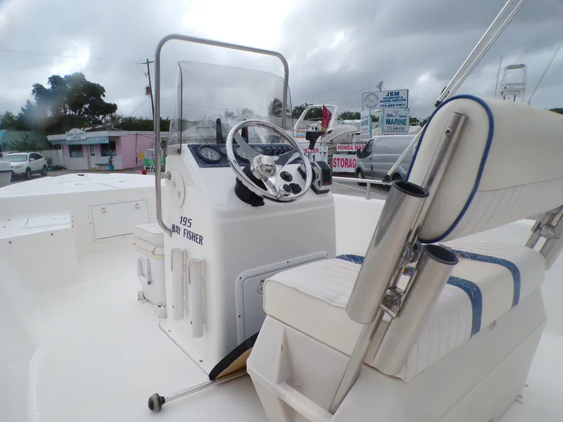 Slide: The Image of 2003 Sea Fox 197 Center Console boat with steering wheel and seating, under cloudy sky. - 6