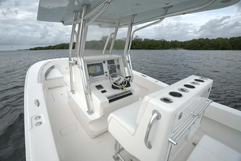 Slide: The Image of 2012 Invincible 33 Open Fisherman boat interior with helm, seating, and rod holders on a calm lake. - 30