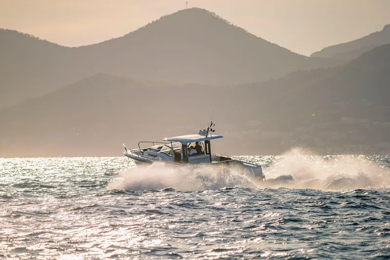 Slide: The Image of Nimbus Tender 11 boat cruising on ocean with scenic mountain backdrop, 2025 model. - 26