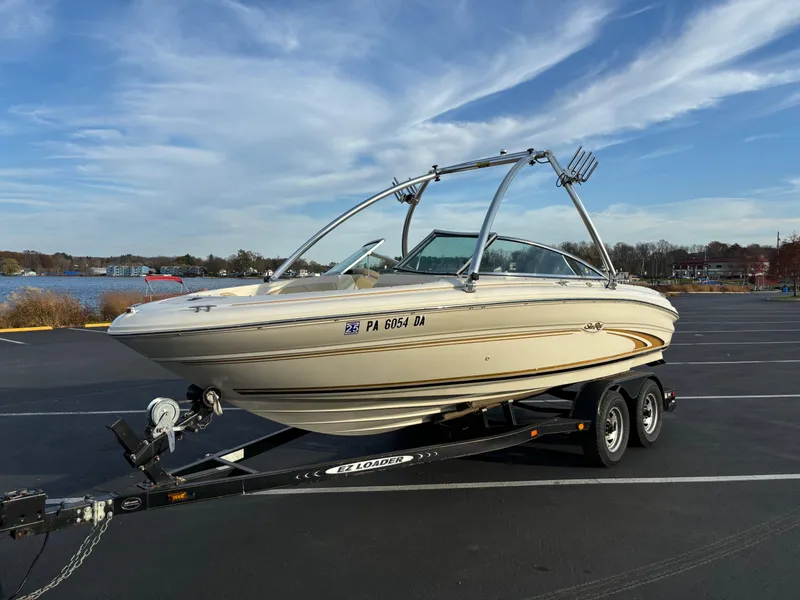 Slide: The Image of 1999 Sea Ray 190 Bow Rider on trailer, parked near a lake under a blue sky. - 9