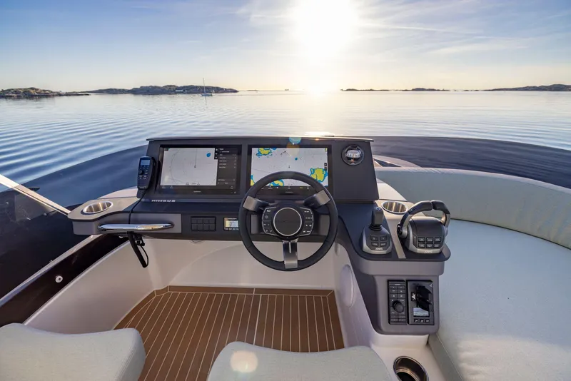 Slide: The Image of Nimbus 495 Flybridge 2025 helm with navigation screens, steering wheel, and serene ocean view. - 30