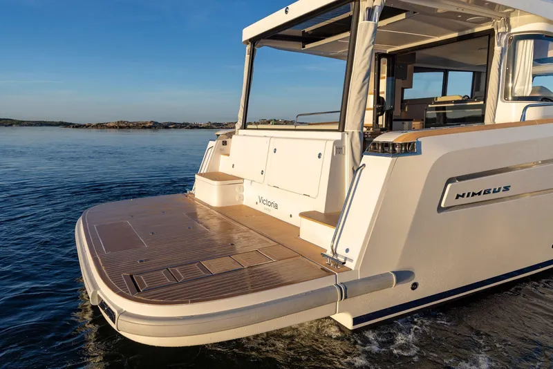 Slide: The Image of Nimbus 495 Flybridge 2025 yacht on calm water, showcasing elegant design and spacious deck. - 9