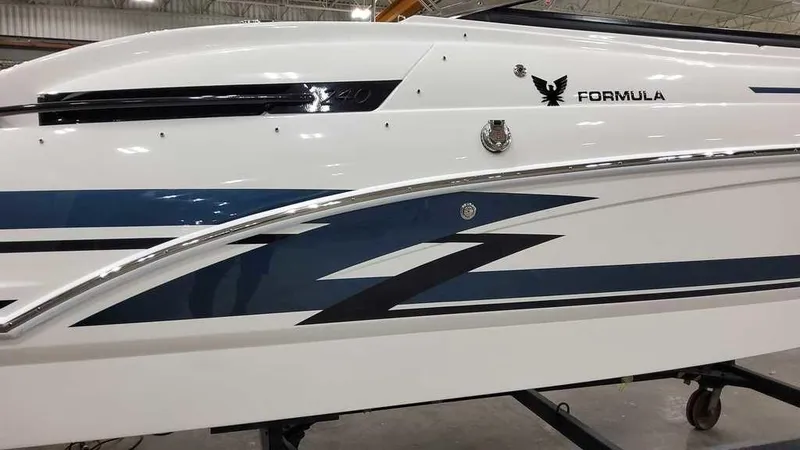 Slide: The Image of 2025 Formula 240 Bowrider boat with sleek blue and white design in a showroom. - 4
