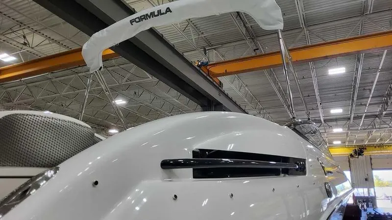 Slide: The Image of 2025 Formula 240 Bowrider boat in showroom, sleek design under industrial lighting. - 5