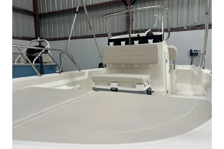 Slide: The Image of 2025 Boston Whaler 150 Montauk boat interior with seating and console in a warehouse. - 11