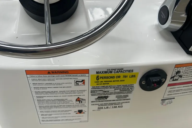 Slide: The Image of 2025 Boston Whaler 150 Montauk steering wheel and capacity warning labels. - 16