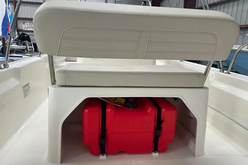 Slide: The Image of 2025 Boston Whaler 150 Montauk boat interior with cushioned seat and red storage container. - 19