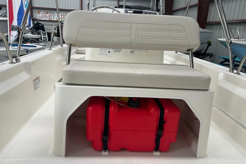 Slide: The Image of 2025 Boston Whaler 150 Montauk boat interior with cushioned seating and storage compartment. - 20