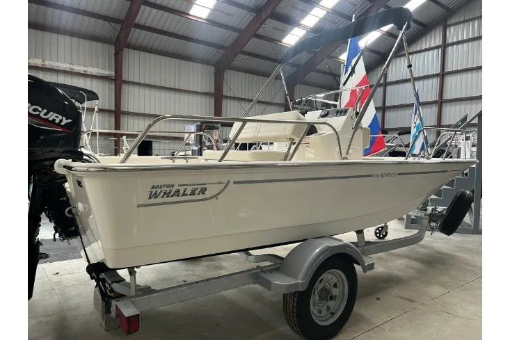 Slide: The Image of 2025 Boston Whaler 150 Montauk boat on trailer in indoor storage. - 8