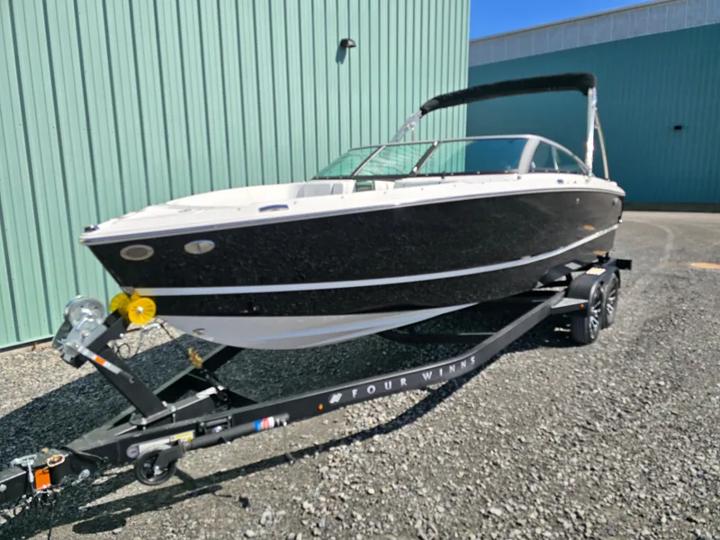 Slide: The Image of 2025 Four Winns H4 boat on trailer, parked outdoors near a green building. - 3