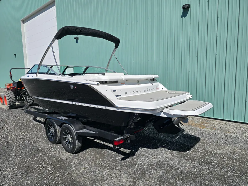Slide: The Image of 2025 Four Winns H4 boat on trailer, parked outside a teal building. - 5