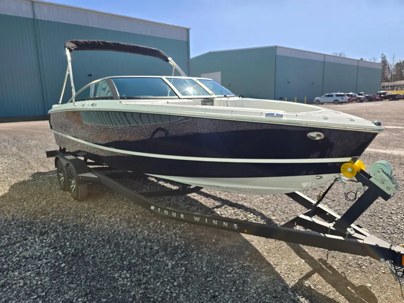 Slide: The Image of 2025 Four Winns H4 boat on trailer, parked outdoors near industrial buildings. - 9